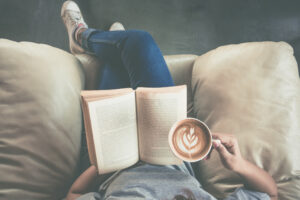 Foto waarop een meisje met een kop koffie in haar hand een van onze favoriete koffie boeken leest