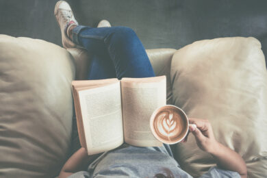 Foto waarop een meisje met een kop koffie in haar hand een van onze favoriete koffie boeken leest