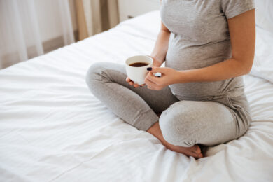 Close-up van een zwangere vrouw die koffie drinkt. Maar hoe lang werkt koffie eigenlijk? En kun je wel koffie drinken als je zwanger bent?