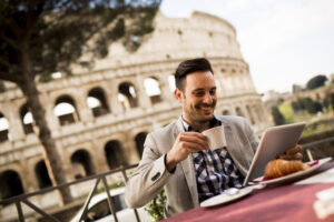 Jonge Italiaanse man die naast het Colosseum in Rome zit. met een kop koffie in zijn hand. Wil jij ook alles leren over Italiaanse koffie etiquette?