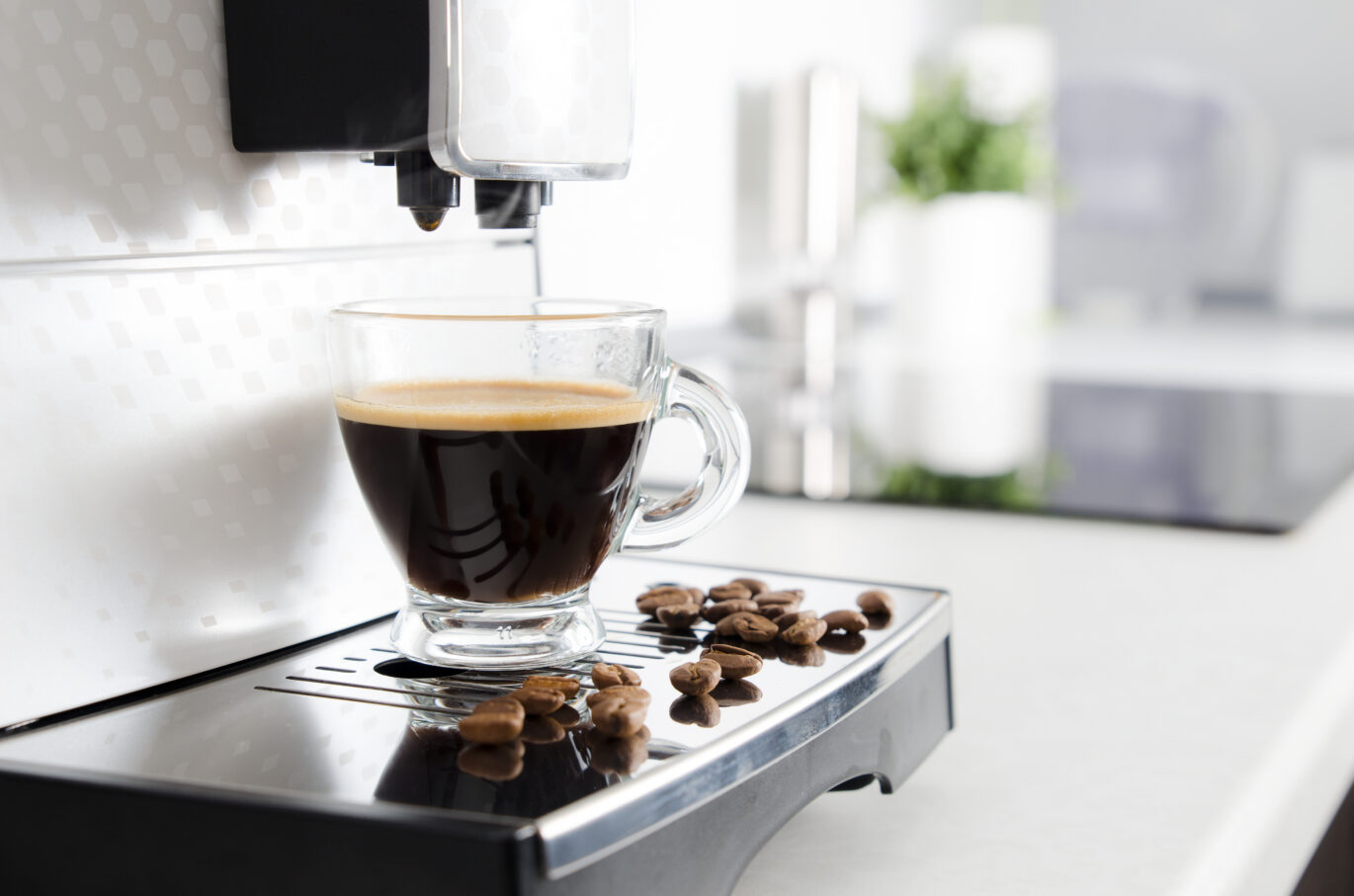 Espresso wordt gezet door een van de beste espressomachines van 2022. IHet glas vult zich met lekkere espresso, terwijl er een paar bonen naast het glas liggen